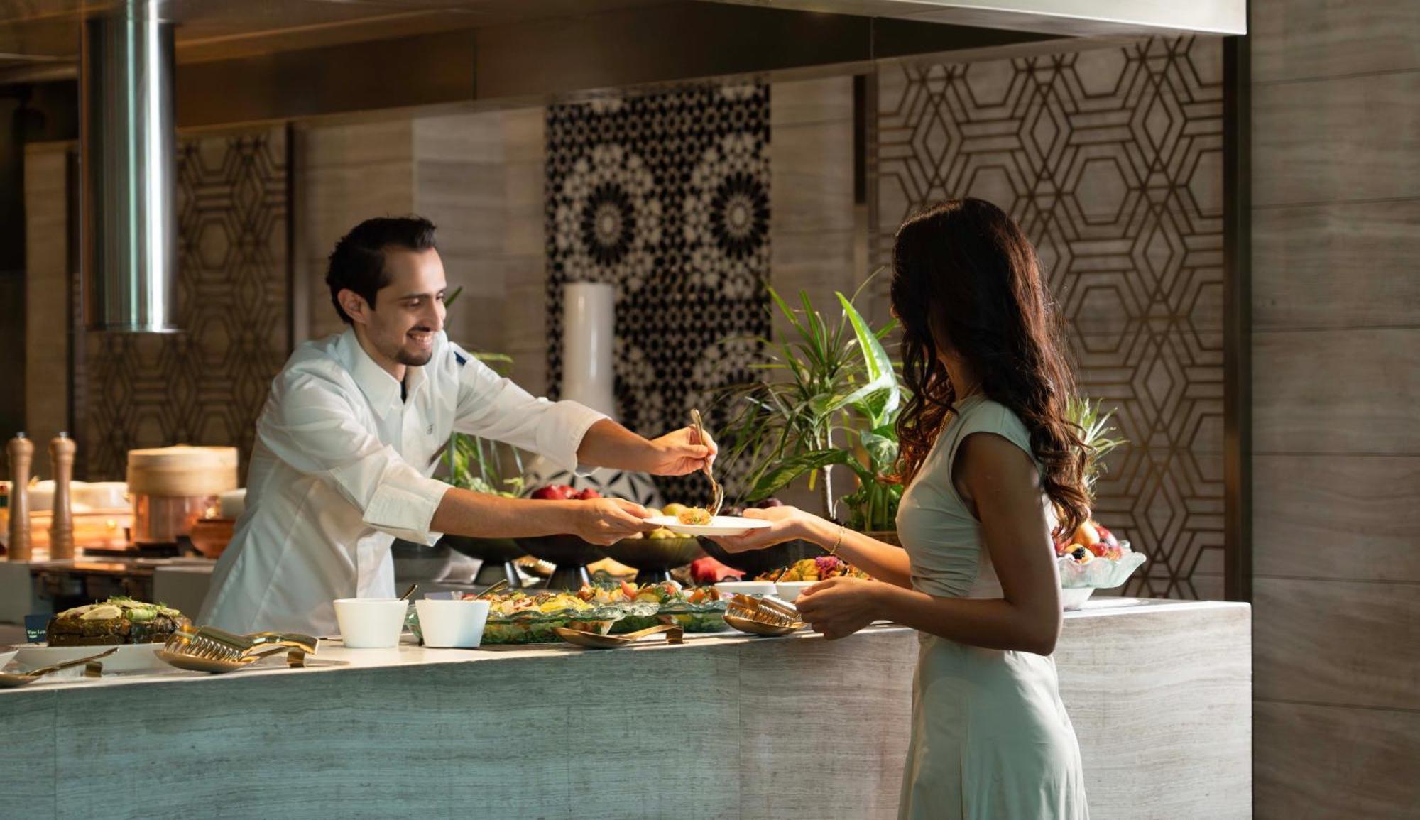 Fairmont Rijád Kültér fotó A chef serving a guest at the buffet